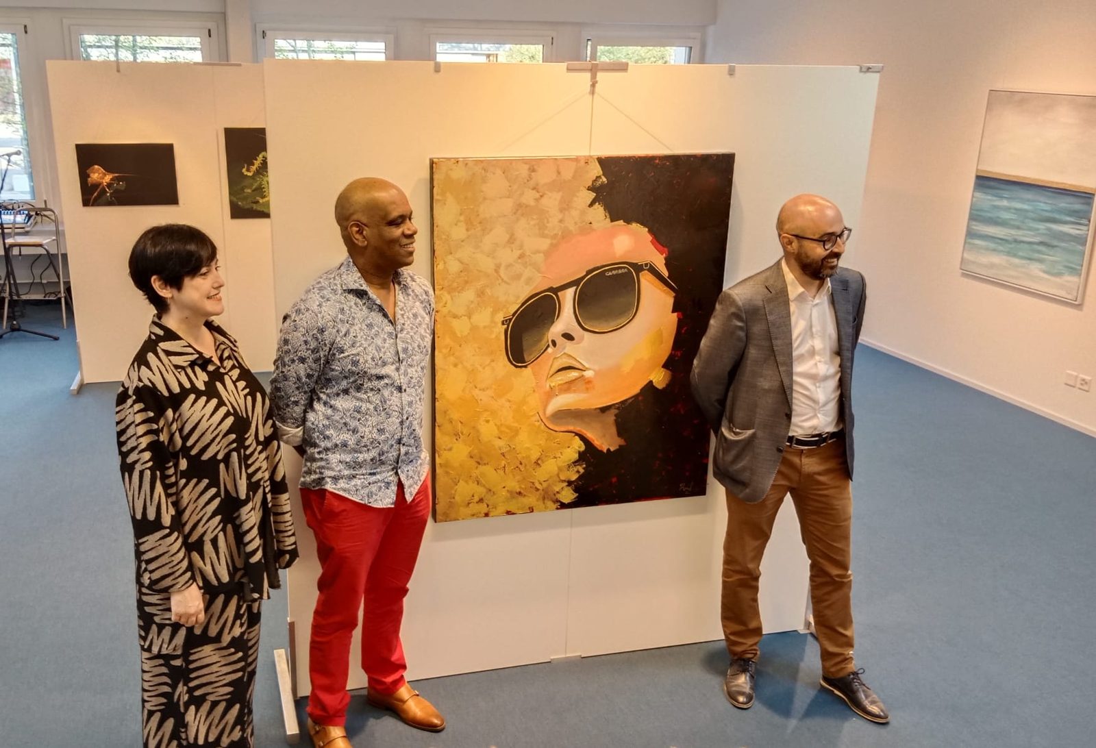 Raúl with two guests in front of the portrait Carrera at the exhibition opening