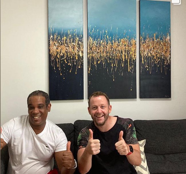 Raúl and a smiling collector giving a thumbs-up below a blue and gold triptych
